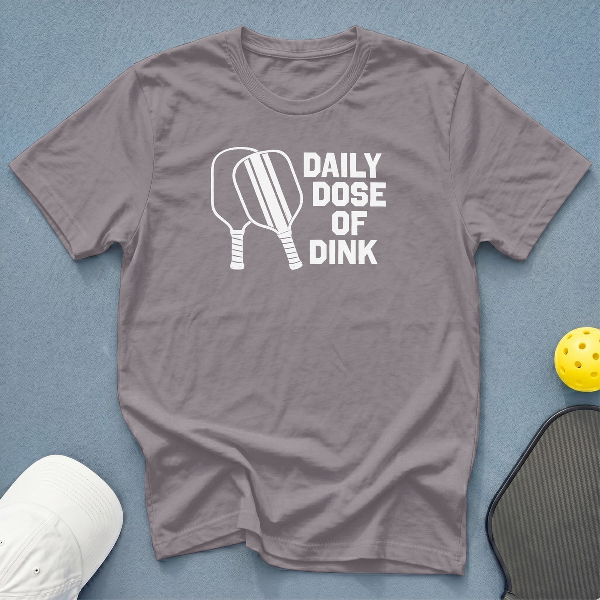 Gray t-shirt with white text "DAILY DOSE OF DINK" and pickleball paddles.