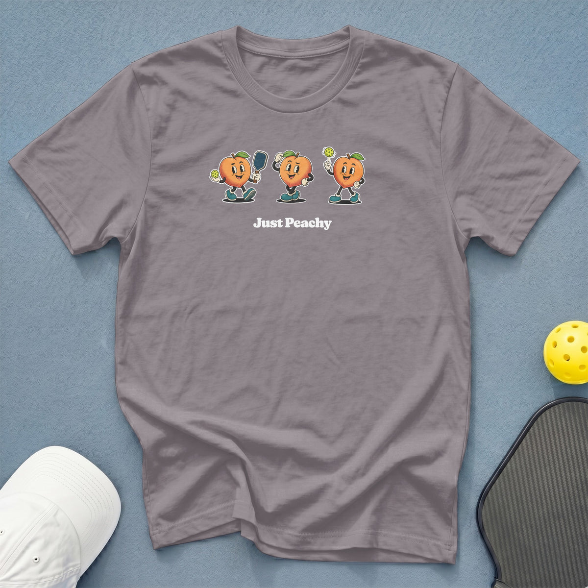 Gray t-shirt with cartoon peaches playing pickleball and text "Just Peachy".