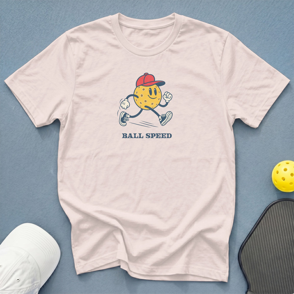 White t-shirt with cartoon pickleball wearing a red hat and text "BALL SPEED".