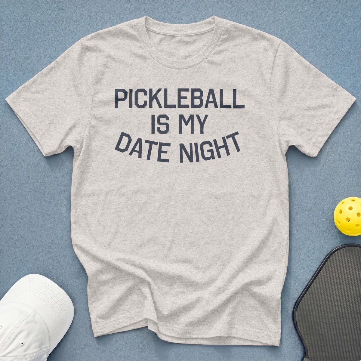 Light grey t-shirt with "Pickleball Is My Date Night" text, pickleball, paddle, and cap.