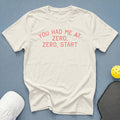 Cream t-shirt with coral text "YOU HAD ME AT ZERO, ZERO, START."