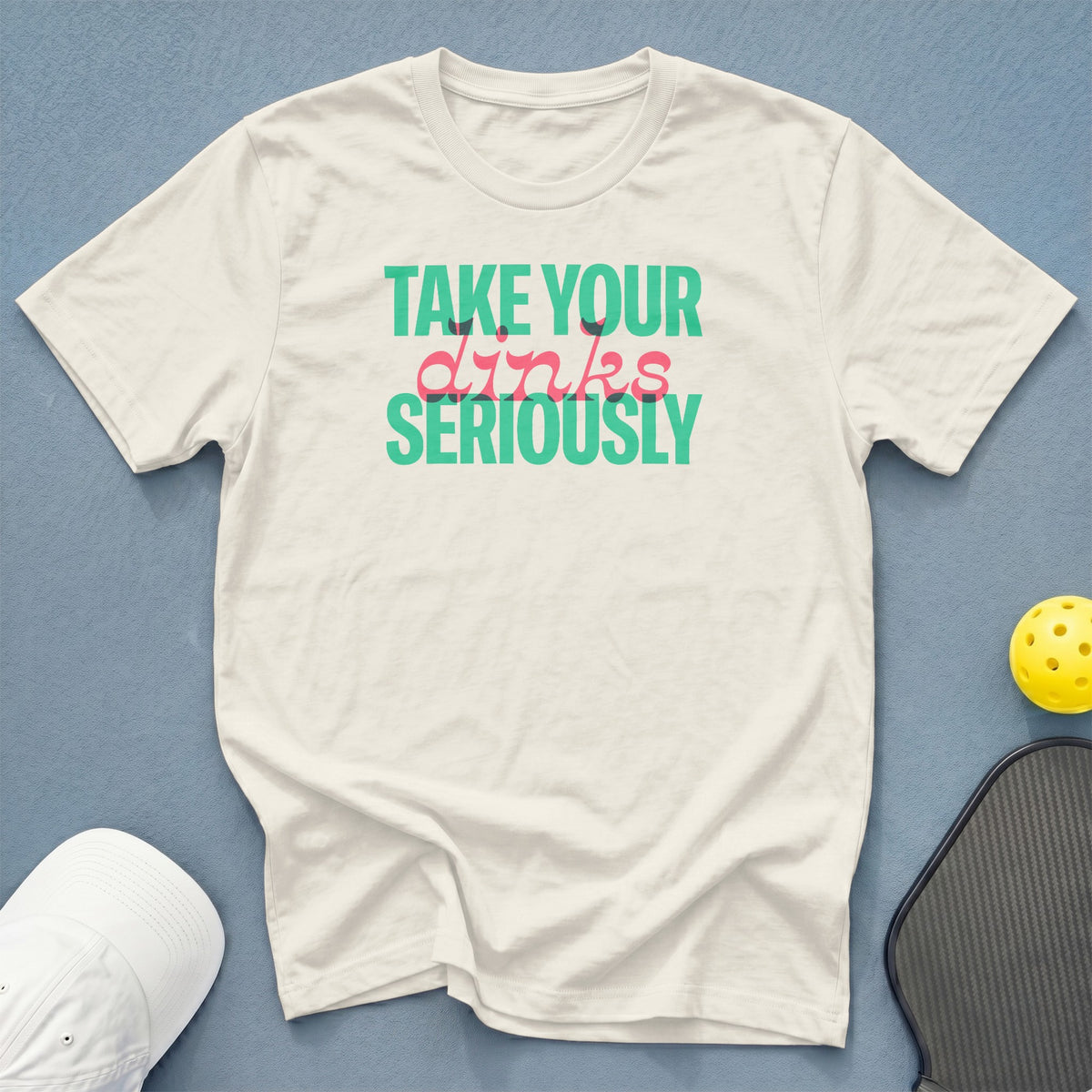 White t-shirt with "TAKE YOUR dinks SERIOUSLY" text, pickleball paddle, and yellow ball.