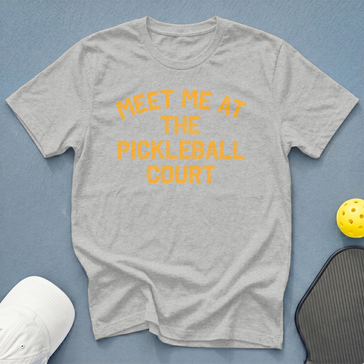 Grey t-shirt with orange text reading "MEET ME AT THE PICKLEBALL COURT".