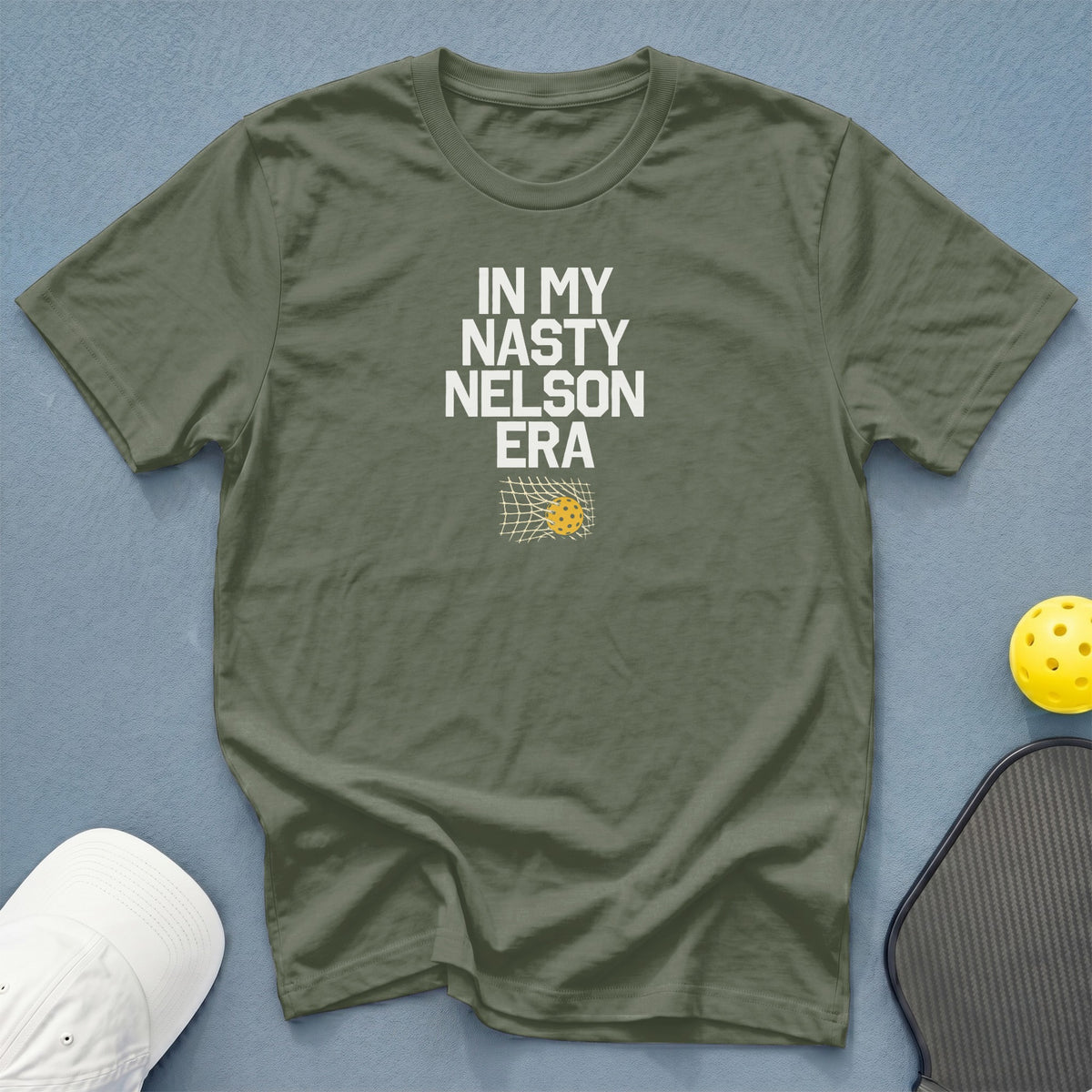 Olive green t-shirt with "IN MY NASTY NELSON ERA" text and pickleball graphic.