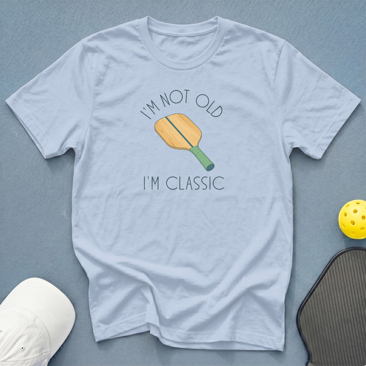 Light blue t-shirt with pickleball paddle graphic and text "I'M NOT OLD I'M CLASSIC".
