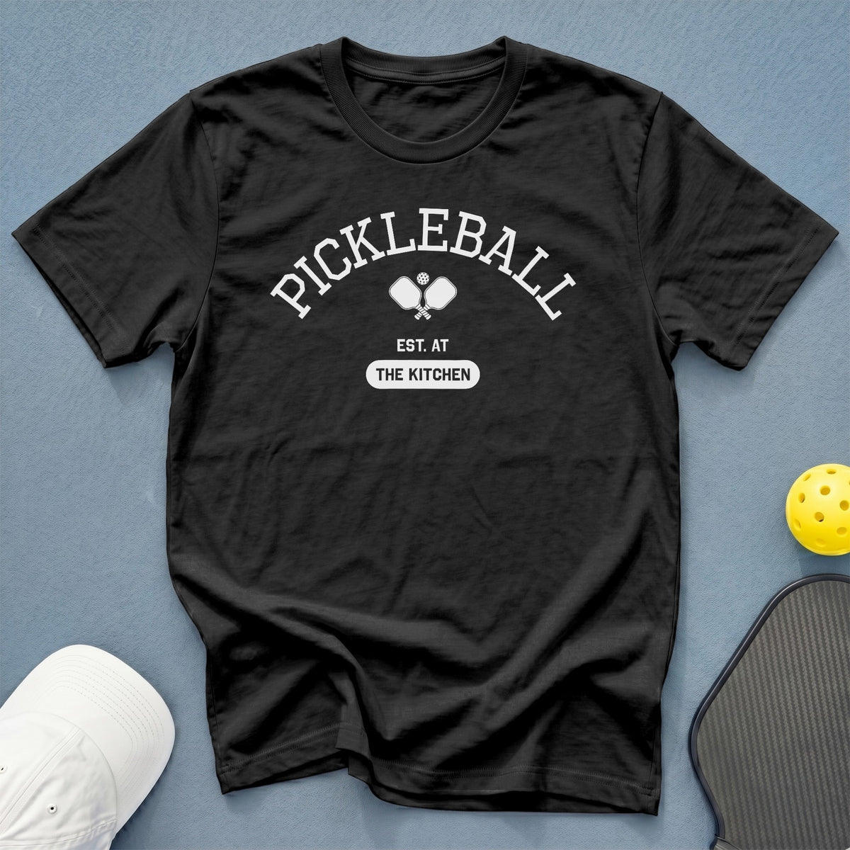 Black t-shirt with "Pickleball Est. At The Kitchen" graphic and crossed paddles.