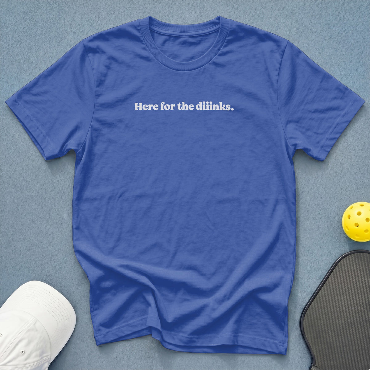 Blue t-shirt with "Here for the diiinks." text, pickleball paddle, and ball.