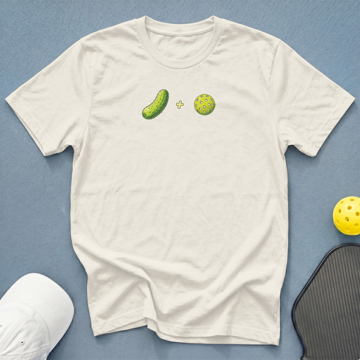 Cream t-shirt with graphic of a pickle and a pickleball on chest.