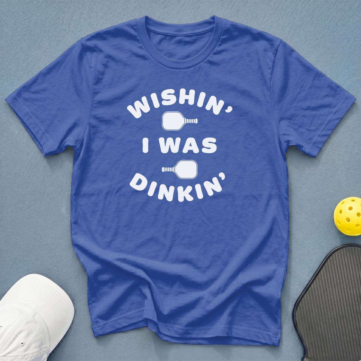 Blue t-shirt with white text "WISHIN, I WAS DINKIN" and pickleball graphics.