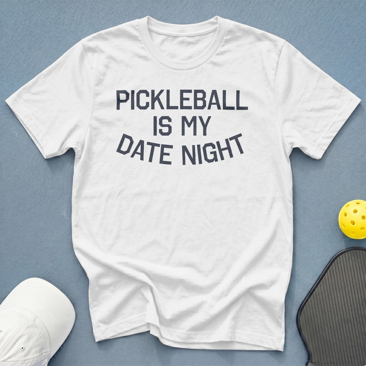 White t-shirt with "PICKLEBALL IS MY DATE NIGHT" text, pickleball, and paddle.