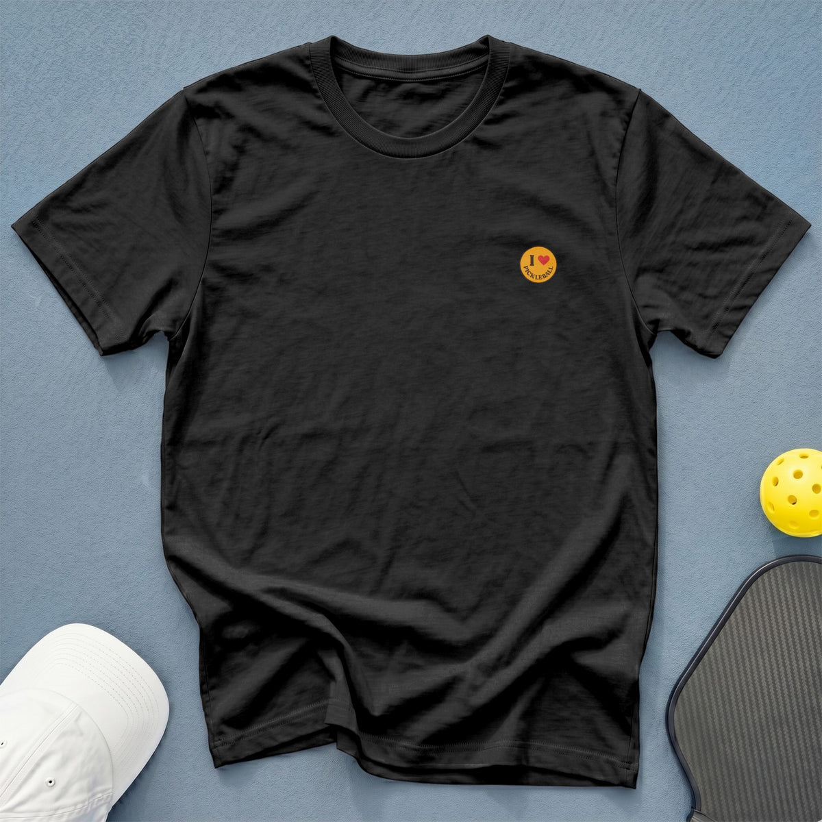 Black t-shirt with "I love pickleball" graphic and pickleball accessories.