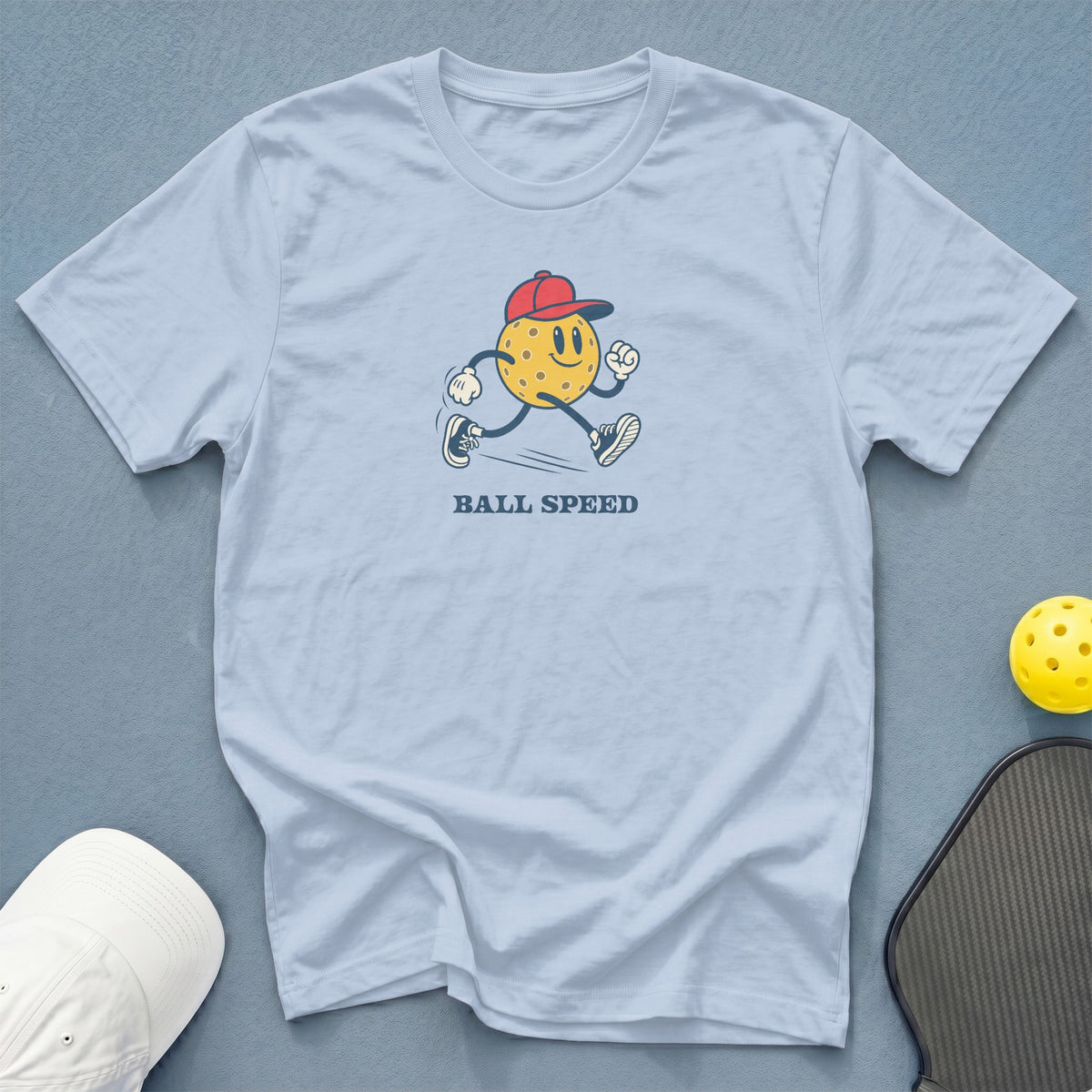 Light blue t-shirt with cartoon pickleball character and "BALL SPEED" text.