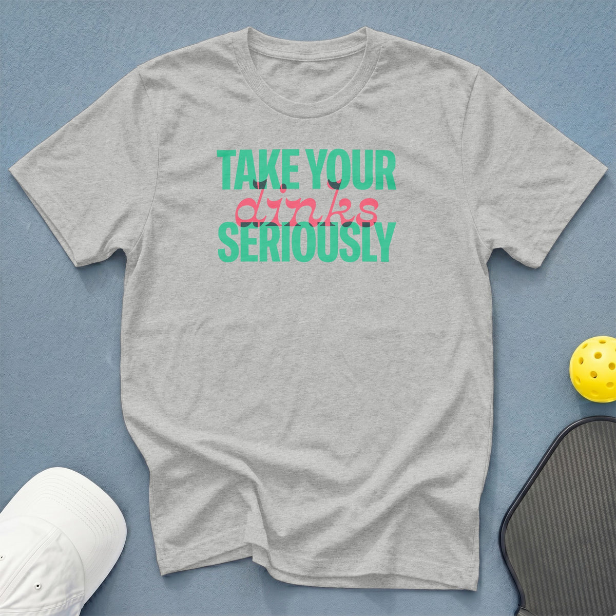 Gray t-shirt with text "TAKE YOUR dinks SERIOUSLY" and pickleball gear.