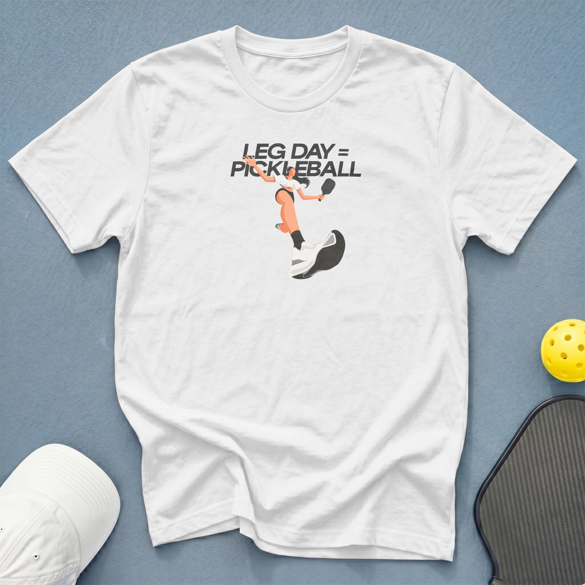 White t-shirt with graphic "LEG DAY = PICKLEBALL" and pickleball player illustration.
