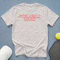 Light grey t-shirt with "PICKLEBALL SQUAD" printed in coral.