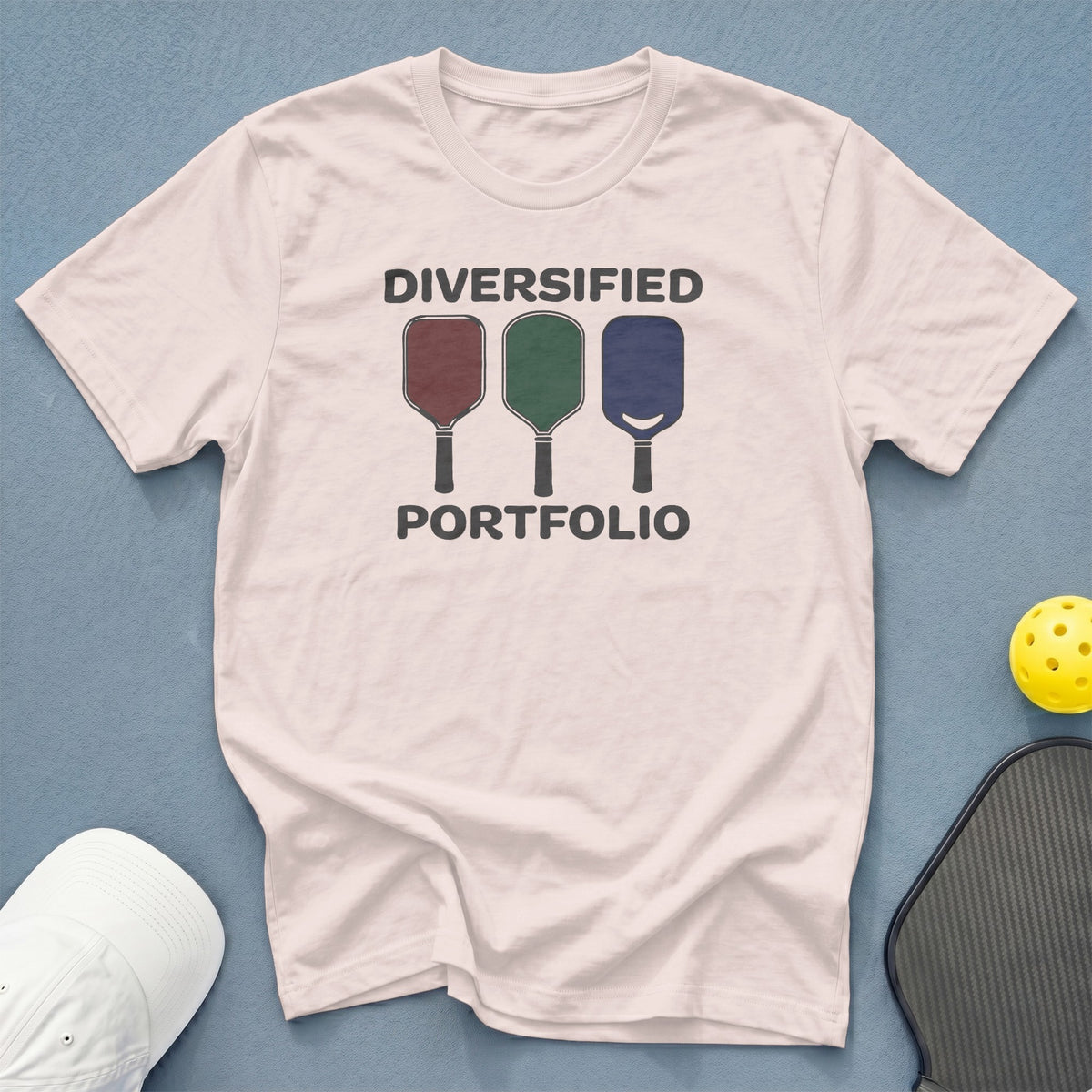 White t-shirt with "DIVERSIFIED PORTFOLIO" and three pickleball paddles graphic.