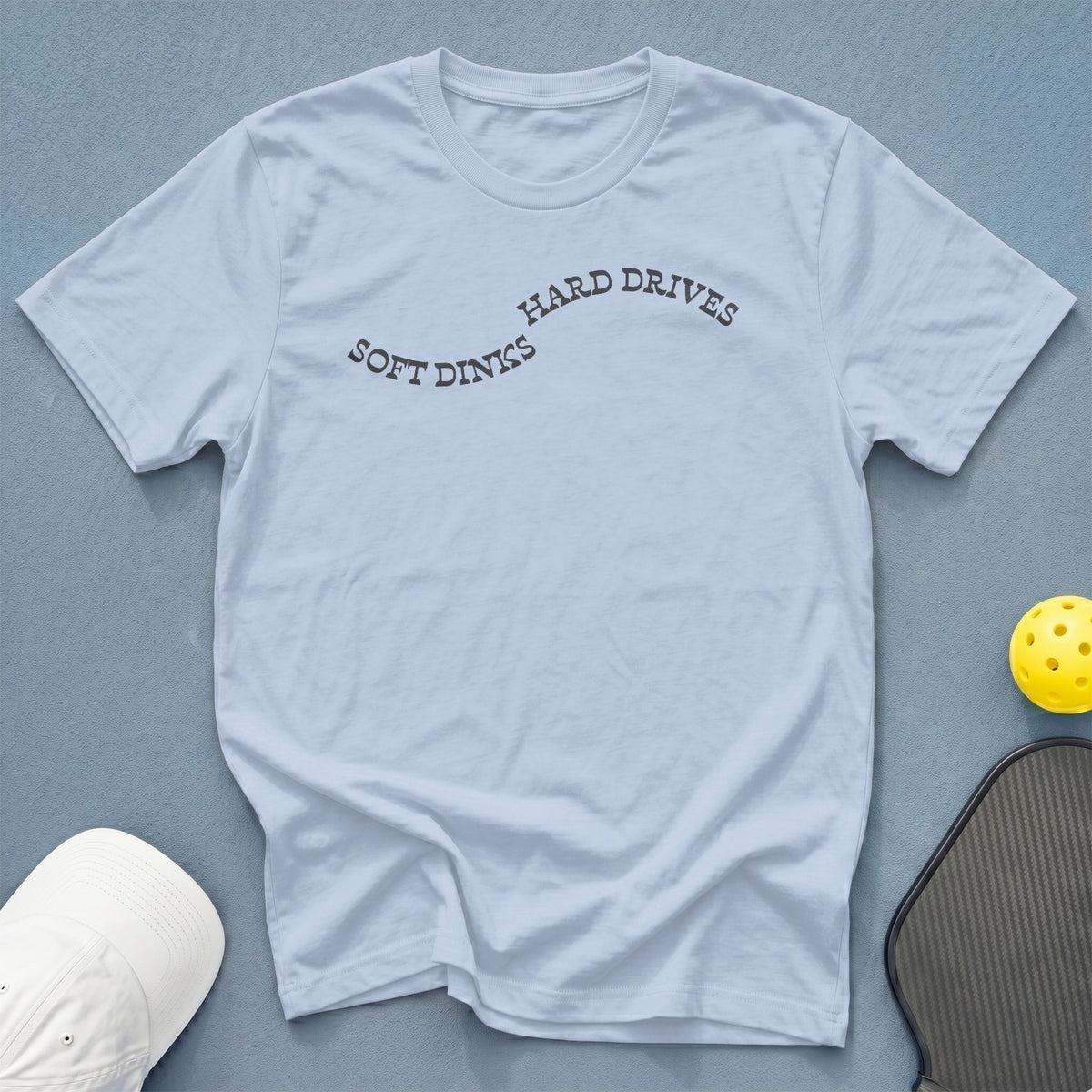 Light blue t-shirt with "SOFT DINKS HARD DRIVES" text and pickleball gear.