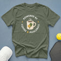 Olive green t-shirt with "Powered by Coffee & Pickleball" text and graphic.