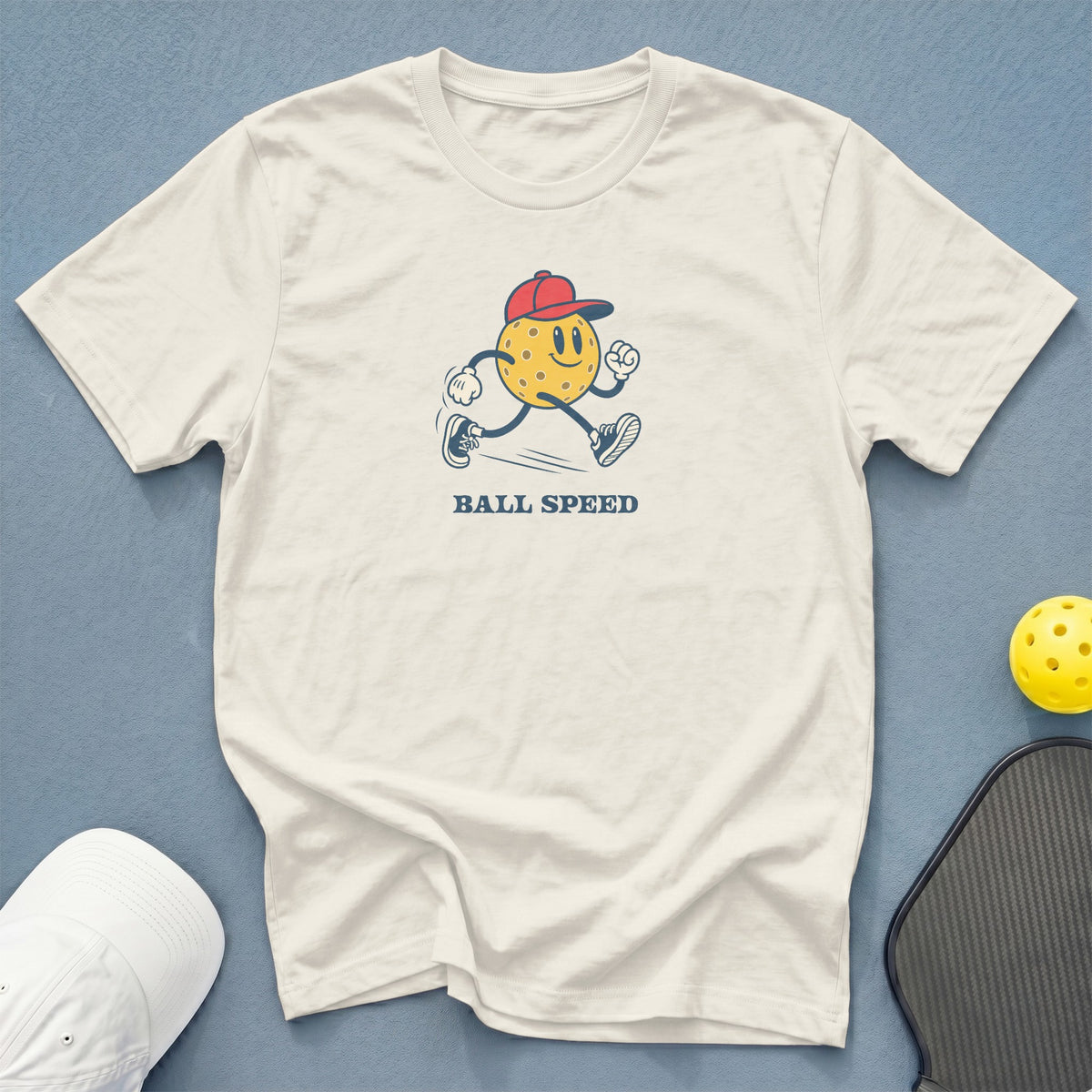 Cream t-shirt with cartoon pickleball running and text "BALL SPEED".