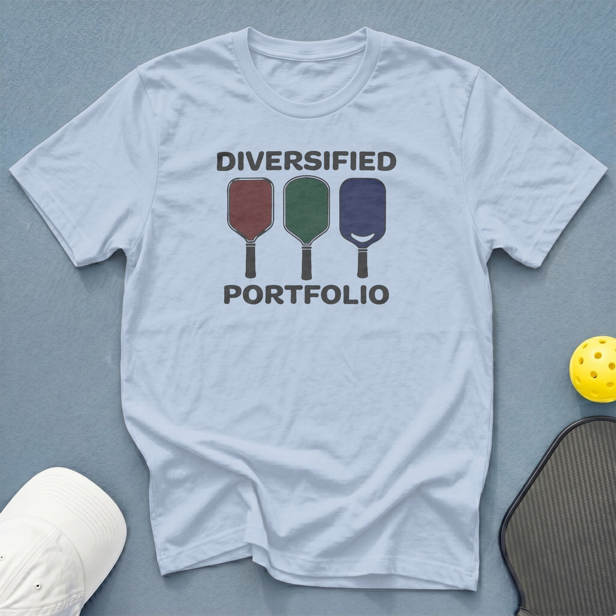Light blue t-shirt with "DIVERSIFIED PORTFOLIO" text and pickleball paddles.