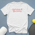 White t-shirt with "Soft dinks & hard drives" text in coral.