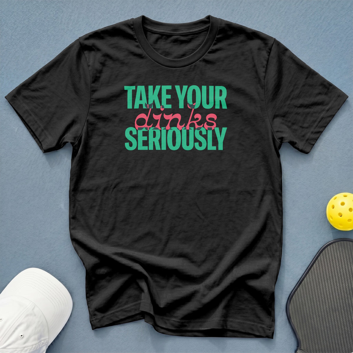 Black t-shirt with "TAKE YOUR dinks SERIOUSLY" text and pickleball accessories.