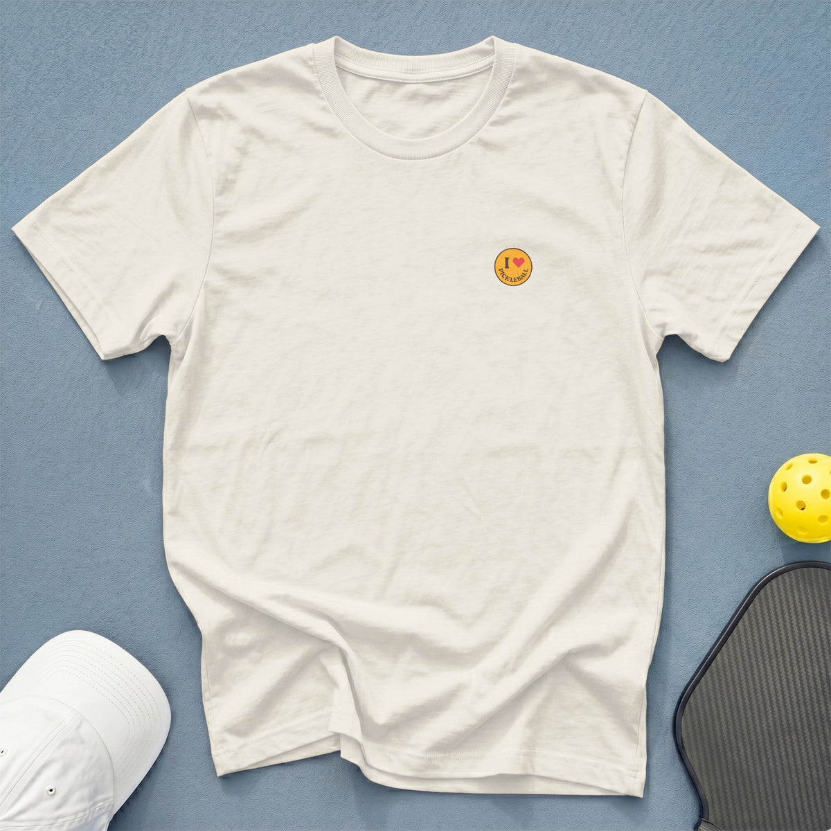 Cream t-shirt with "I love pickleball" embroidered on left chest.
