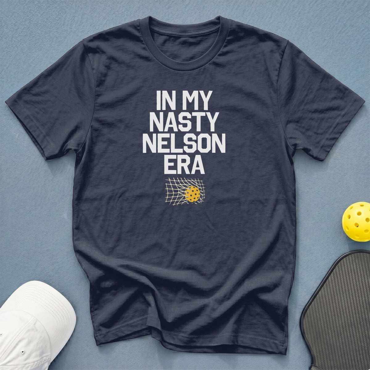 Navy t-shirt with "In My Nasty Nelson Era" text and pickleball in a net.