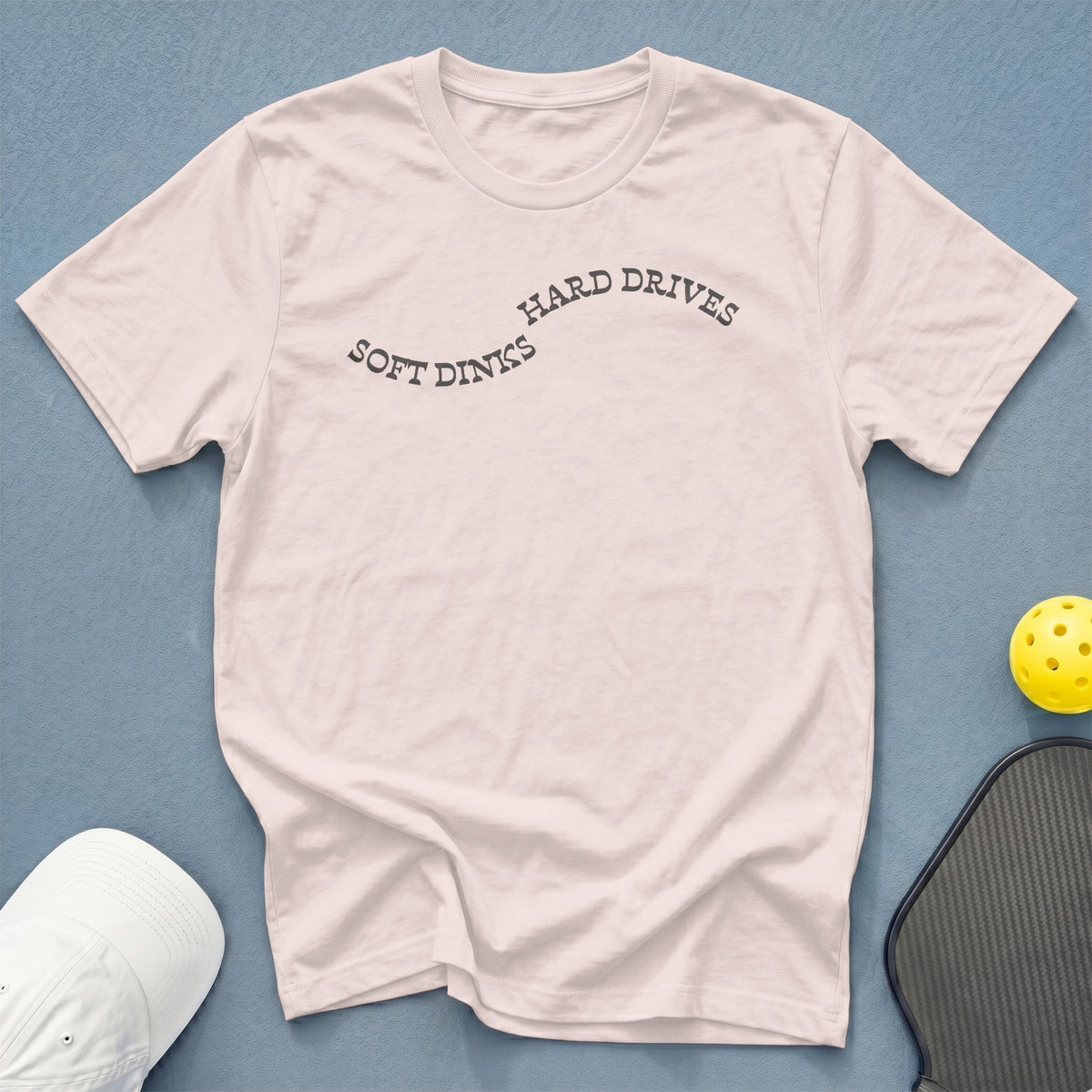 Pink t-shirt with "SOFT DINKS HARD DRIVES" text, pickleball, and hat.