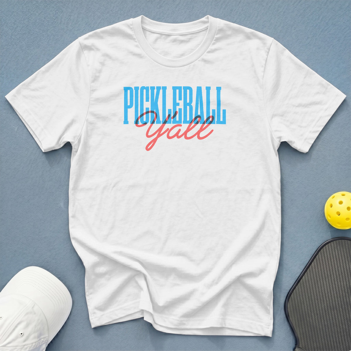 White t-shirt with "PICKLEBALL Y'all" text, pickleball, and paddle.