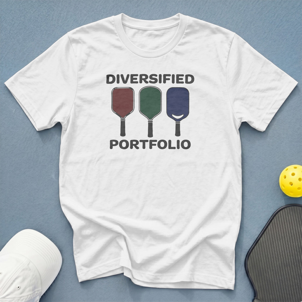 White t-shirt with "DIVERSIFIED PORTFOLIO" and three pickleball paddles.