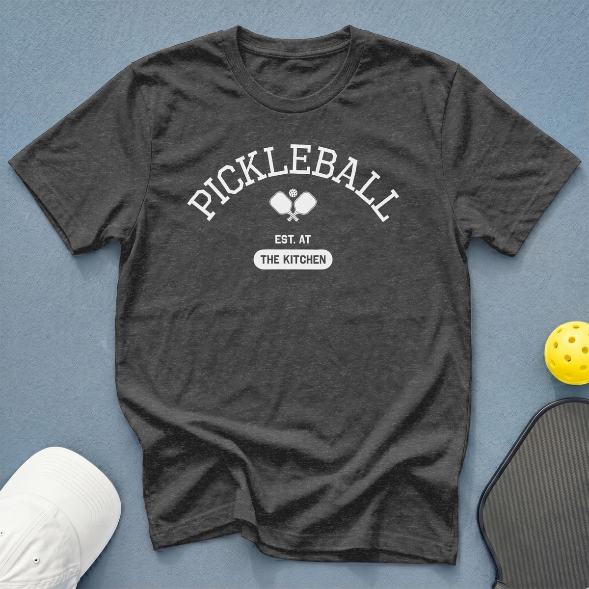 Charcoal t-shirt with white "Pickleball Est. At The Kitchen" text and crossed paddles.