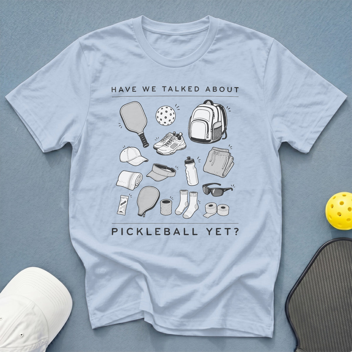 Light blue t-shirt with pickleball gear illustrations and text "HAVE WE TALKED ABOUT PICKLEBALL YET?".