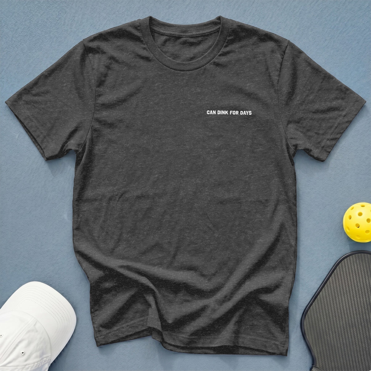 Dark grey t-shirt with white text "CAN DINK FOR DAYS" next to pickleball paddle and ball.