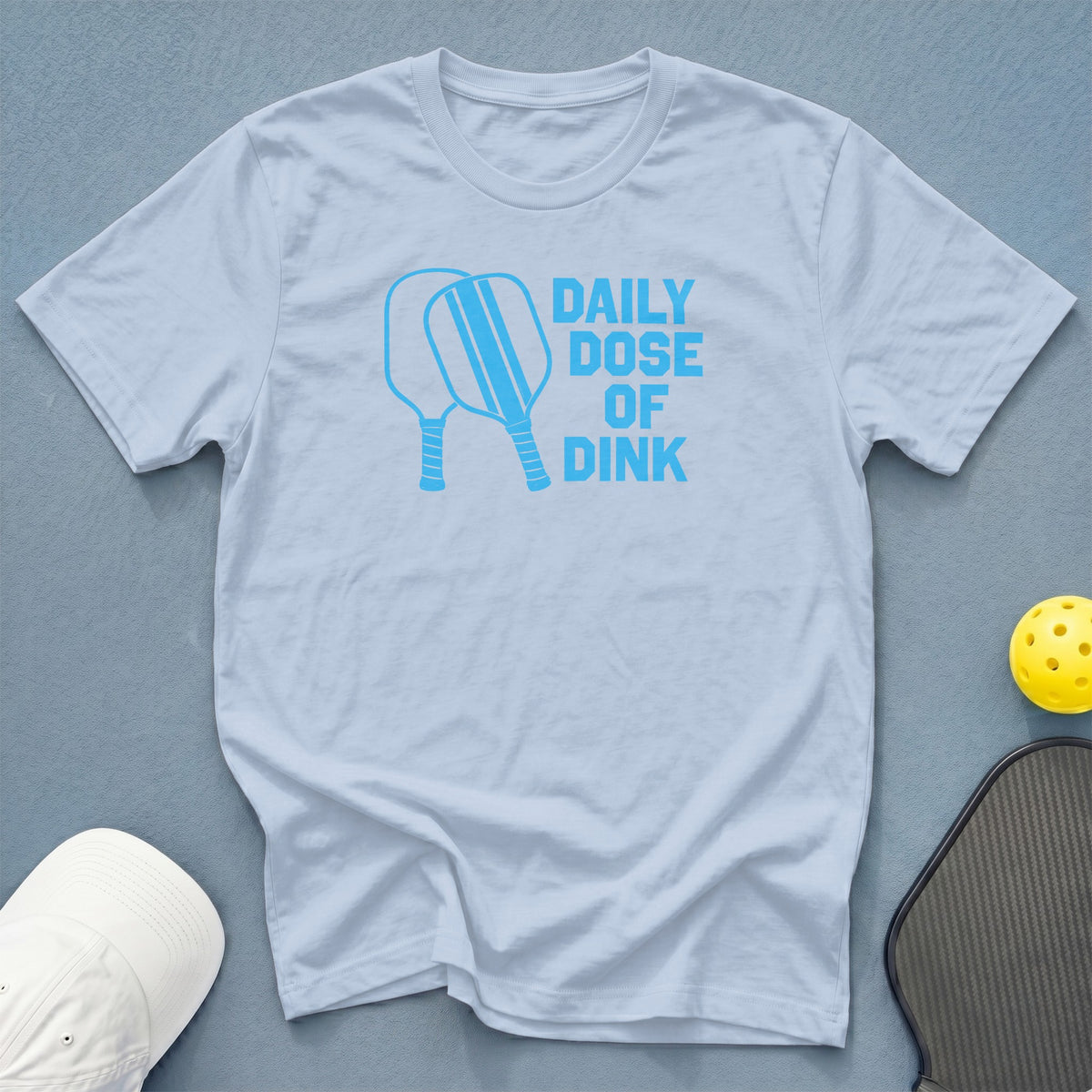 Light blue t-shirt with "Daily Dose of Dink" and pickleball paddles graphic.