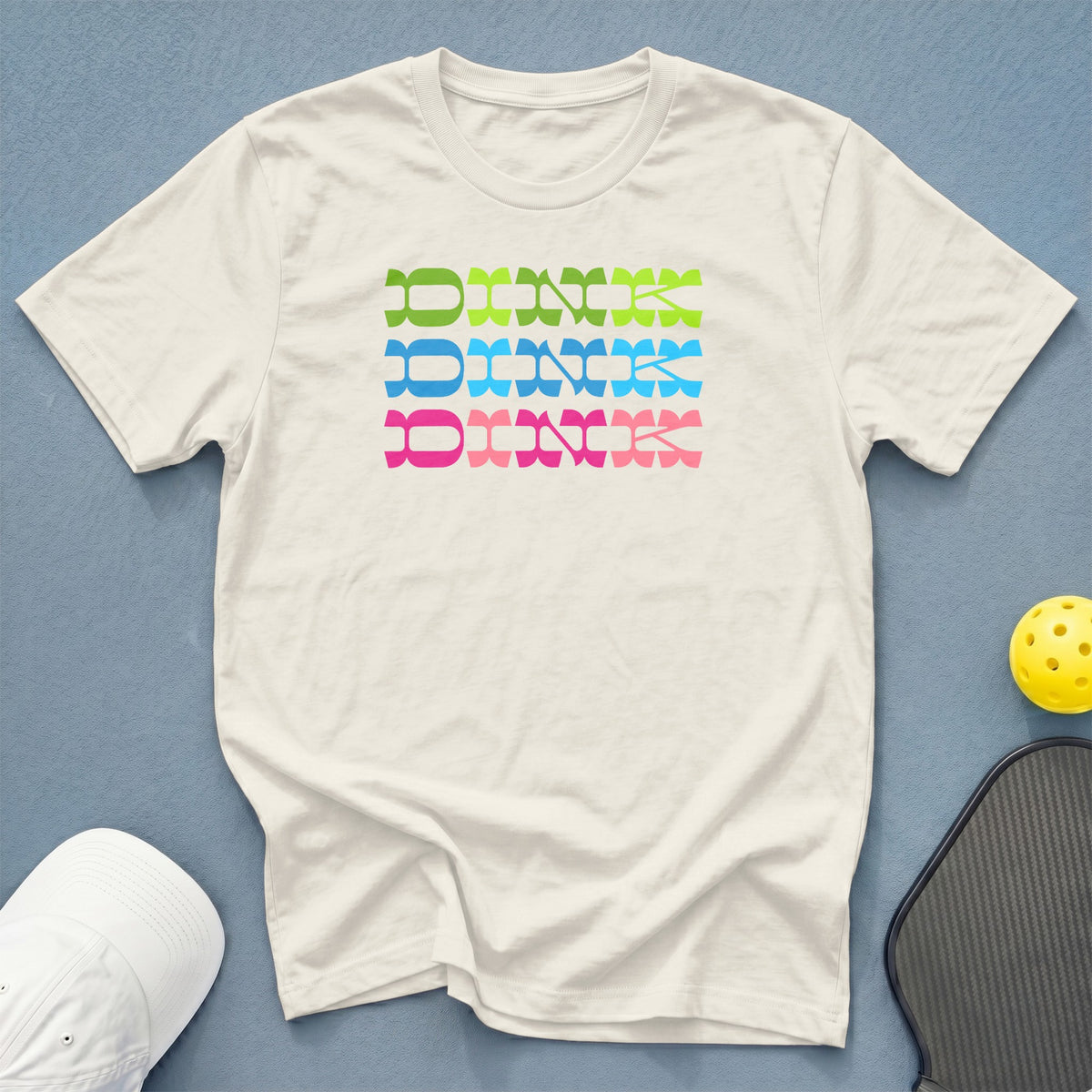 Cream t-shirt with "Dink" in green, blue, and pink stacked lettering.