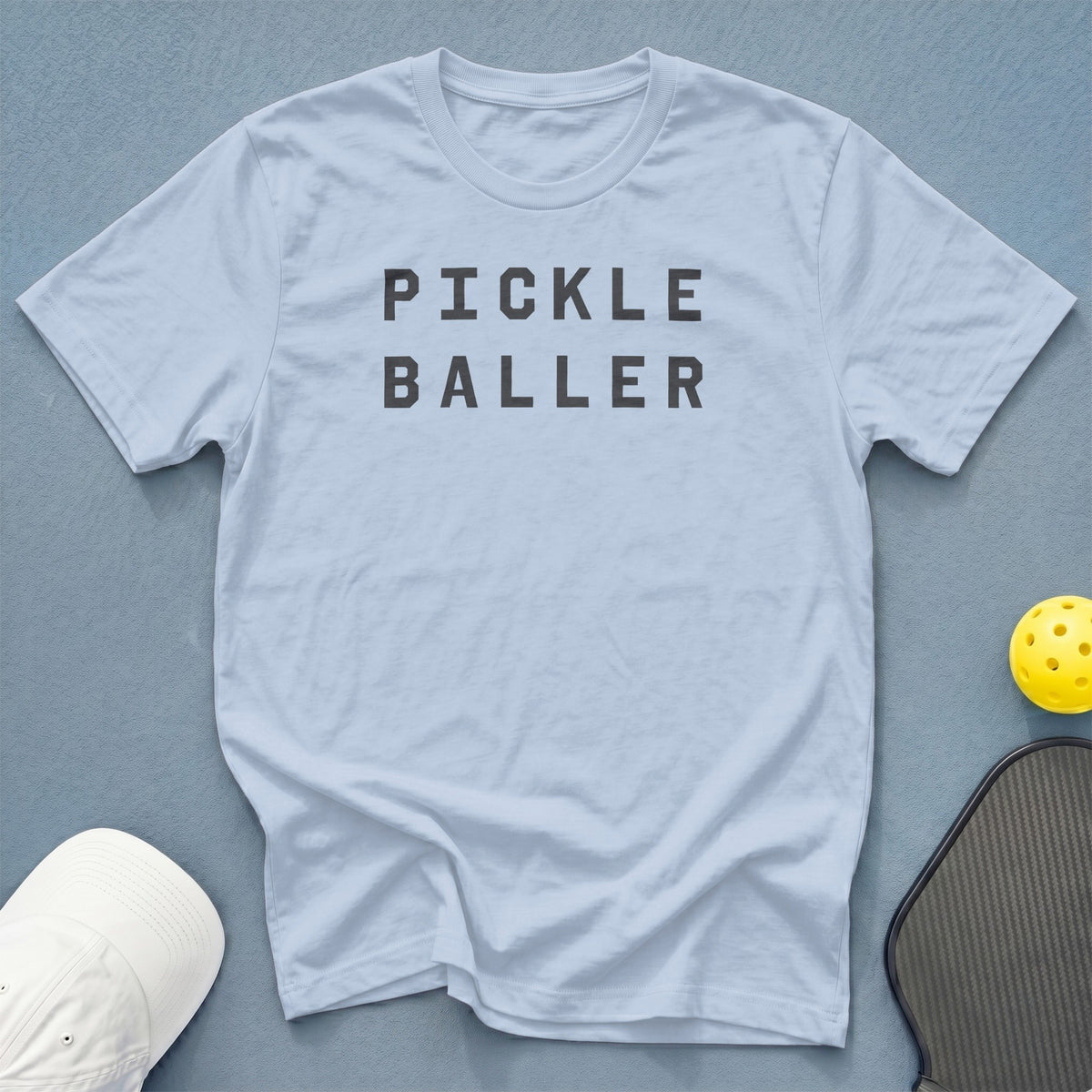 Light blue t-shirt with "PICKLE BALLER" text, pickleball, and paddle.