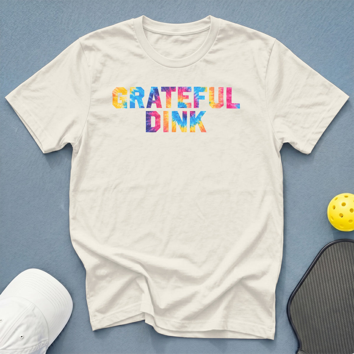 Cream t-shirt with tie-dye "GRATEFUL DINK" text, pickleball paddle, and ball.