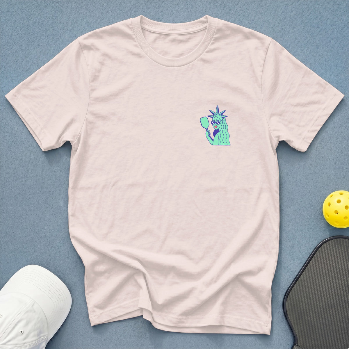 Light pink t-shirt with a Statue of Liberty graphic holding a pickleball paddle.