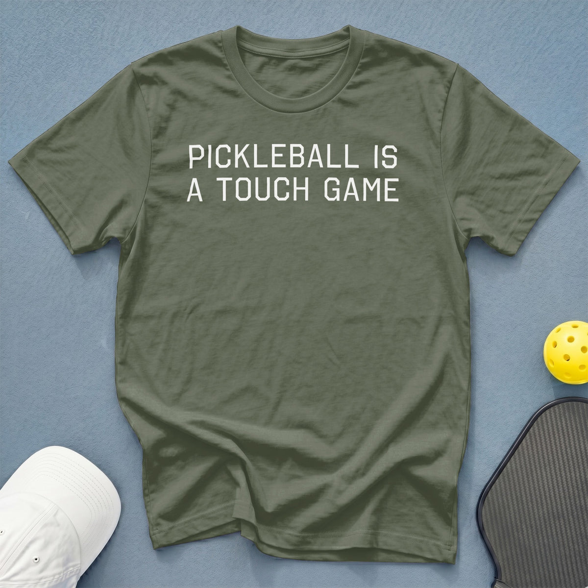 Olive green t-shirt with white text "PICKLEBALL IS A TOUCH GAME".