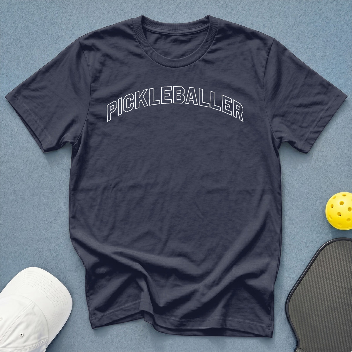 Navy t-shirt with white "PICKLEBALLER" text, pickleball, and paddle.