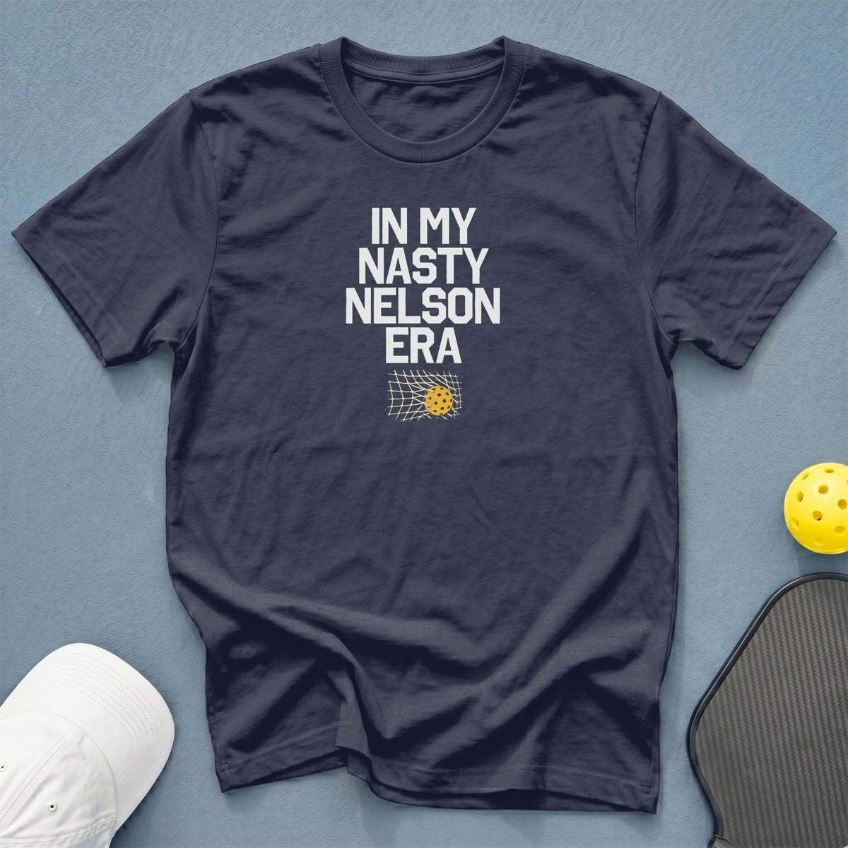 Dark blue t-shirt with "IN MY NASTY NELSON ERA" text and pickleball net graphic.