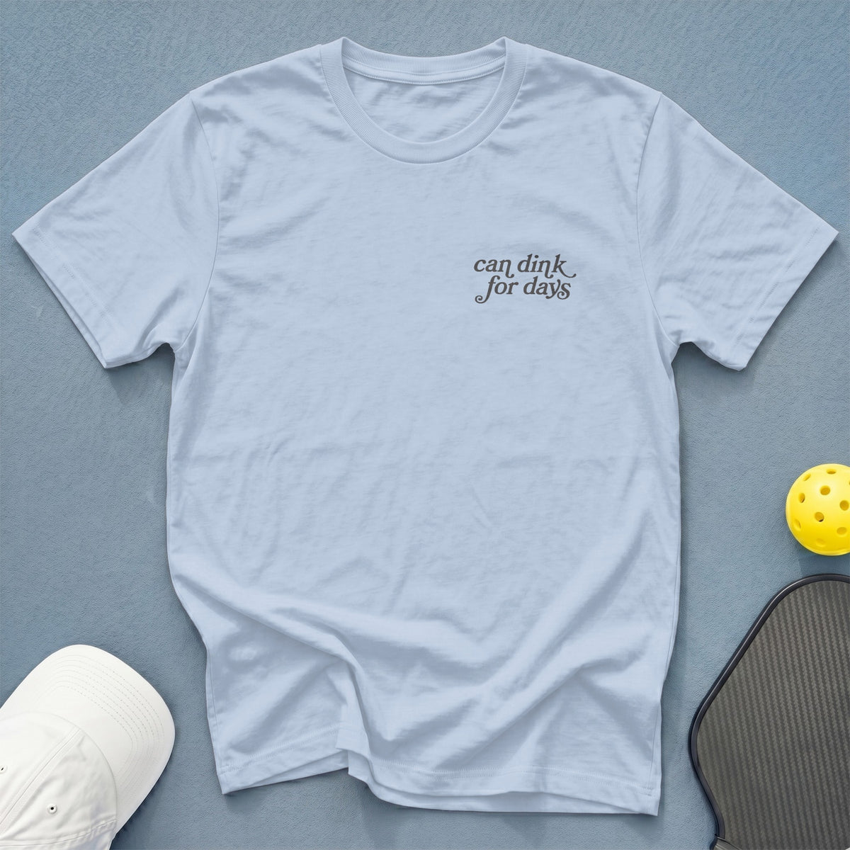 Light blue t-shirt with "can dink for days" text and pickleball equipment.