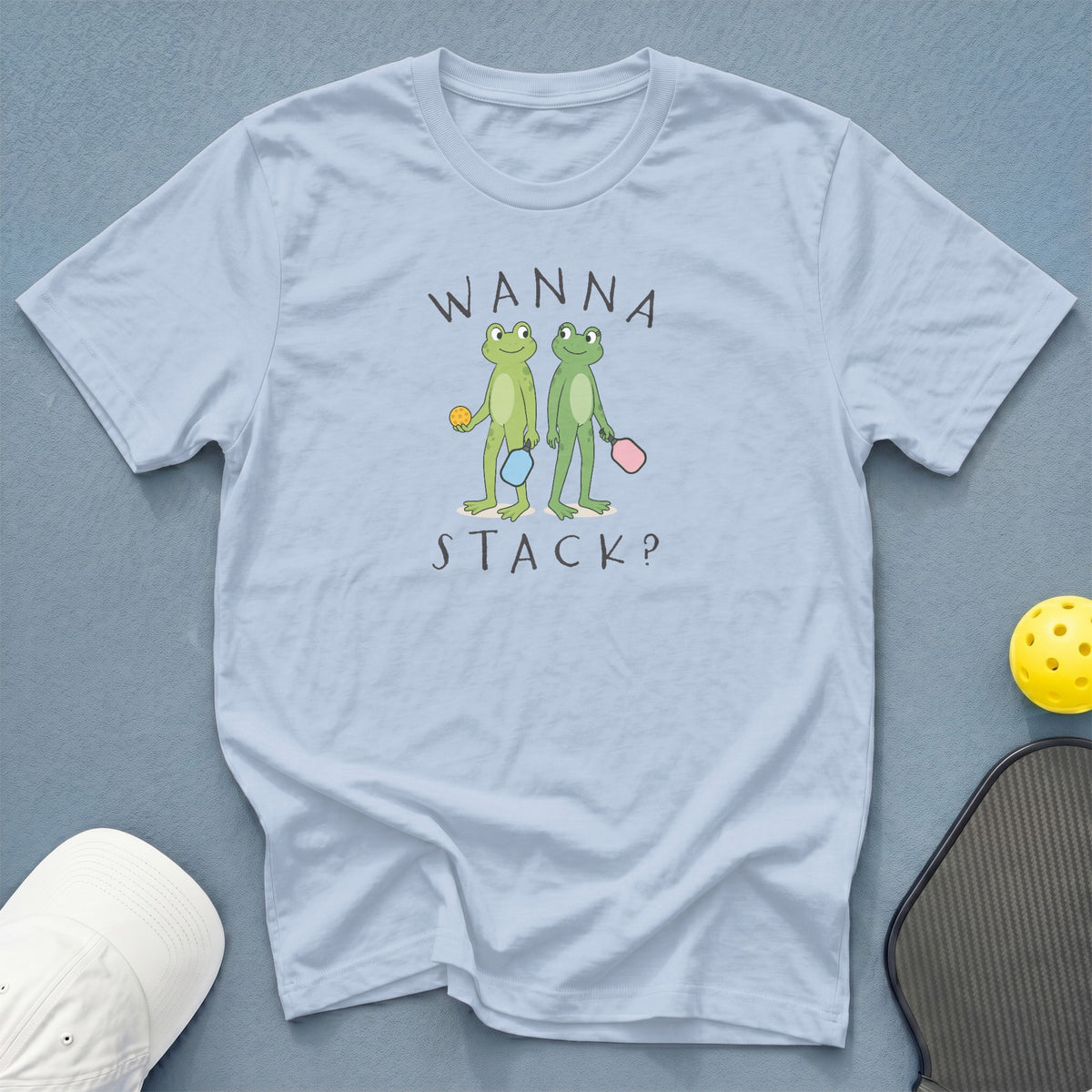 Light blue t-shirt with cartoon frogs playing pickleball and the text "WANNA STACK?".
